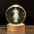 White crystal ball ornament on a wooden base with warm light, showing a detailed Cross design inside.