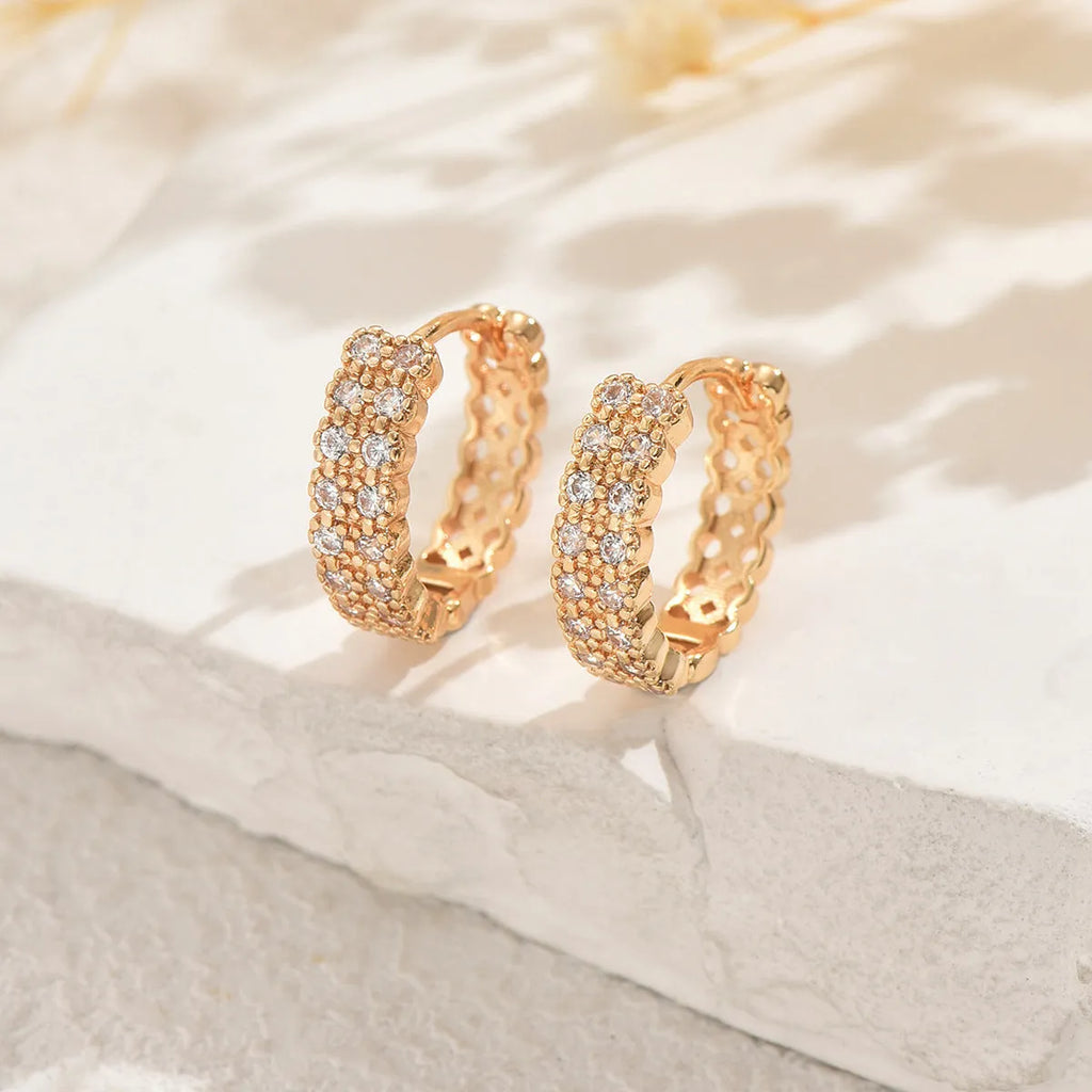A pair of copper geometry pattern ear studs with round, dot, and ring design elements.