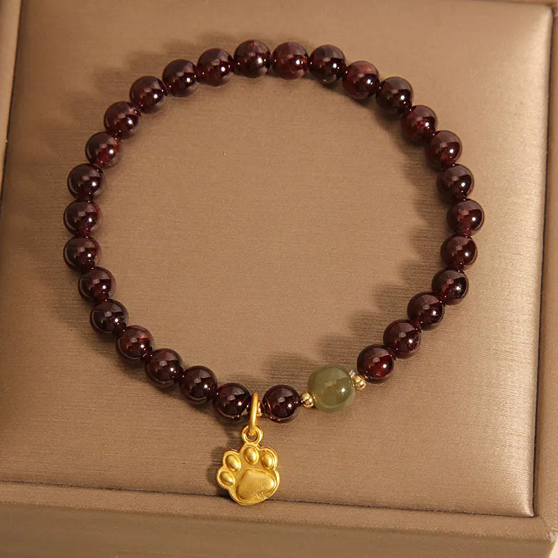 Women's original design Cat's Paw Garnet crystal bracelet on a plain background.