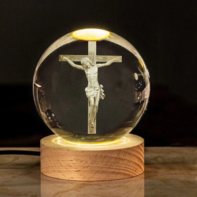 White crystal ball ornament on a wooden base with warm light, showing a detailed Cross design inside.