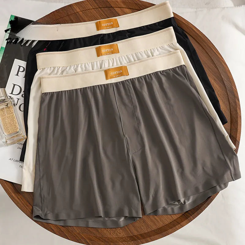 Pack of three men's loose fit ice silk boxer shorts in solid colours on a mid-waist model.