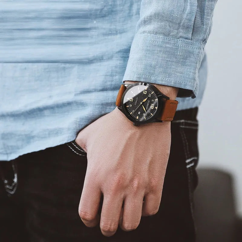 Men's automatic mechanical watch with leather strap on wrist, showing silver case and army green dial option.