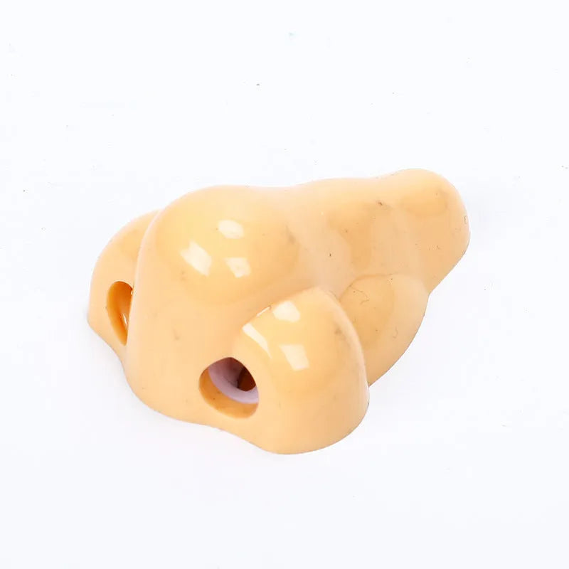 Flesh colour geometric plastic pencil sharpener with large nostril on a white background.