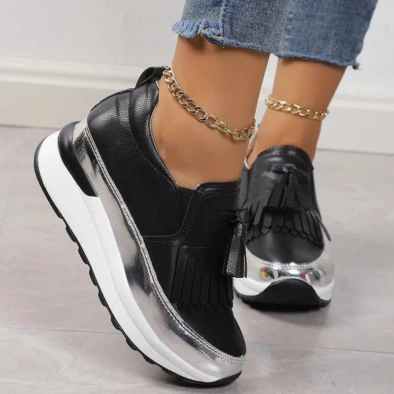 Women's black casual shoes with tassel detail and muffin wedge heel on white background