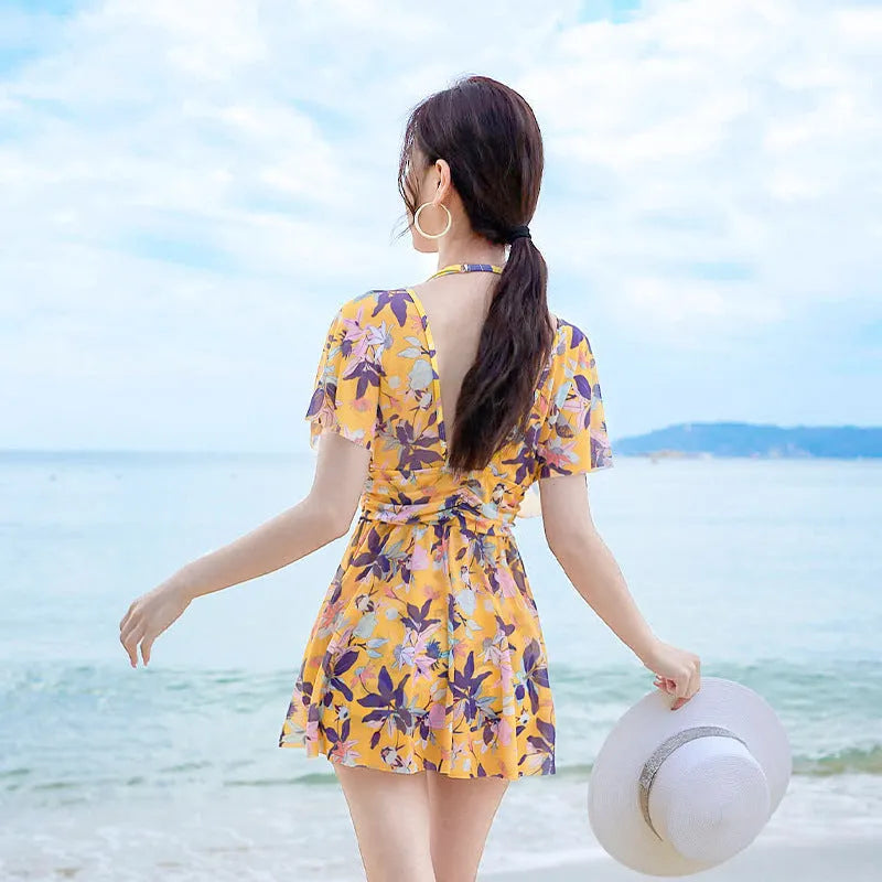 Yellow women's one-piece swimsuit with a floral pattern, shown on a hanger.