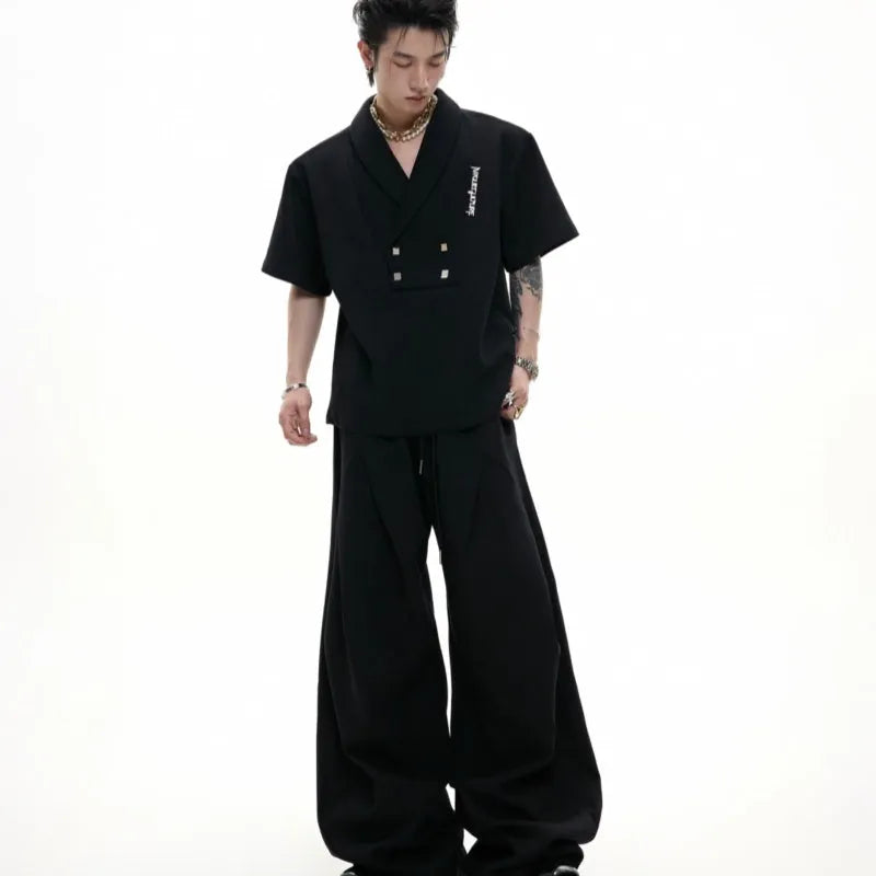 Men's dark grey cotton sports suit with V-neck short sleeve top, padded shoulders, metal embellishments, and matching shorts.