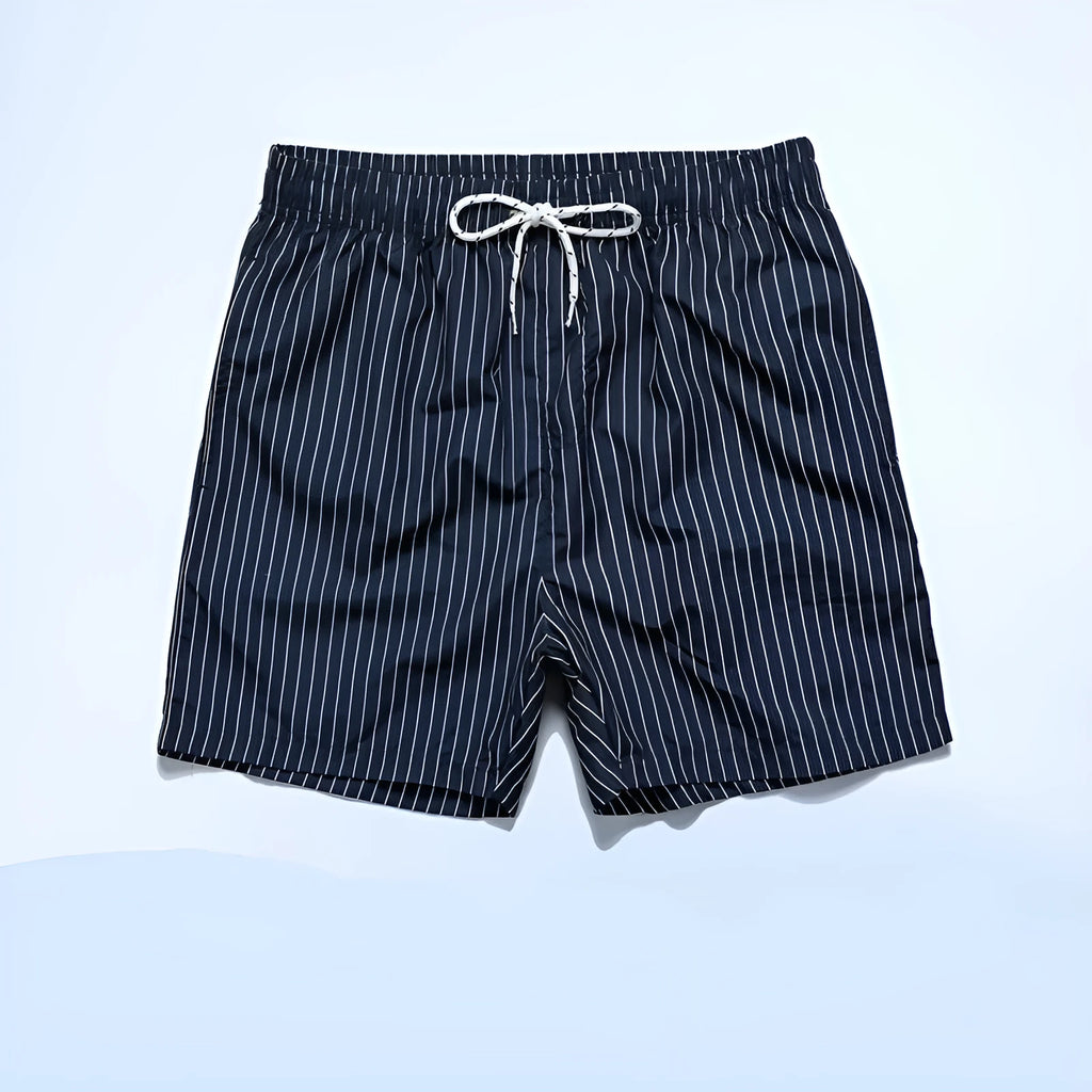 Men's striped polyester shorts in light blue, shown on a beach.