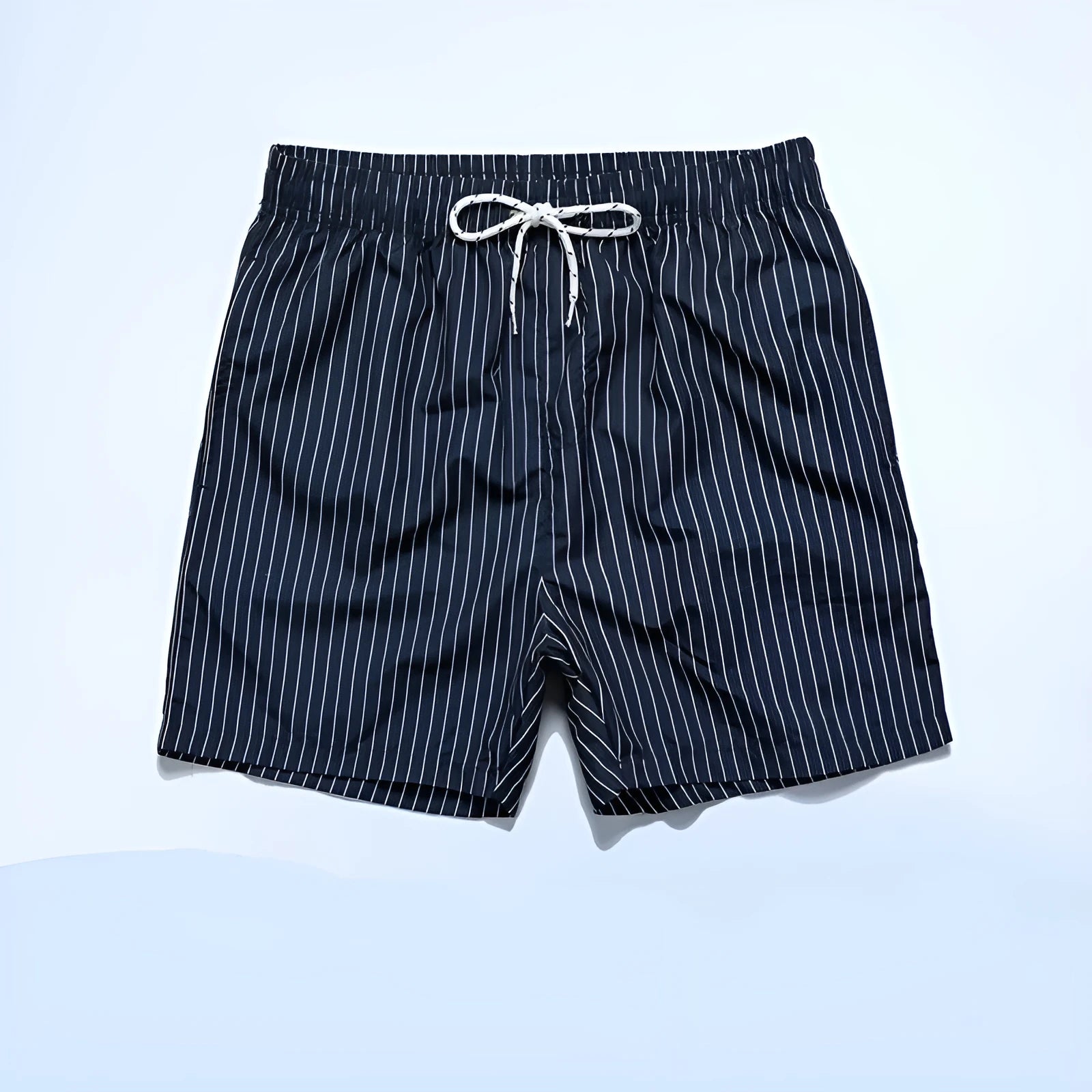 Men's striped polyester shorts in light blue, shown on a beach.
