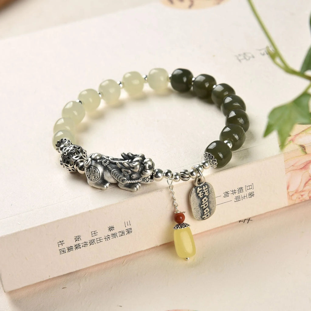 Handmade women's retro bracelet with a natural Hetian jade bead and pure silver coin charm on an adjustable chain.
