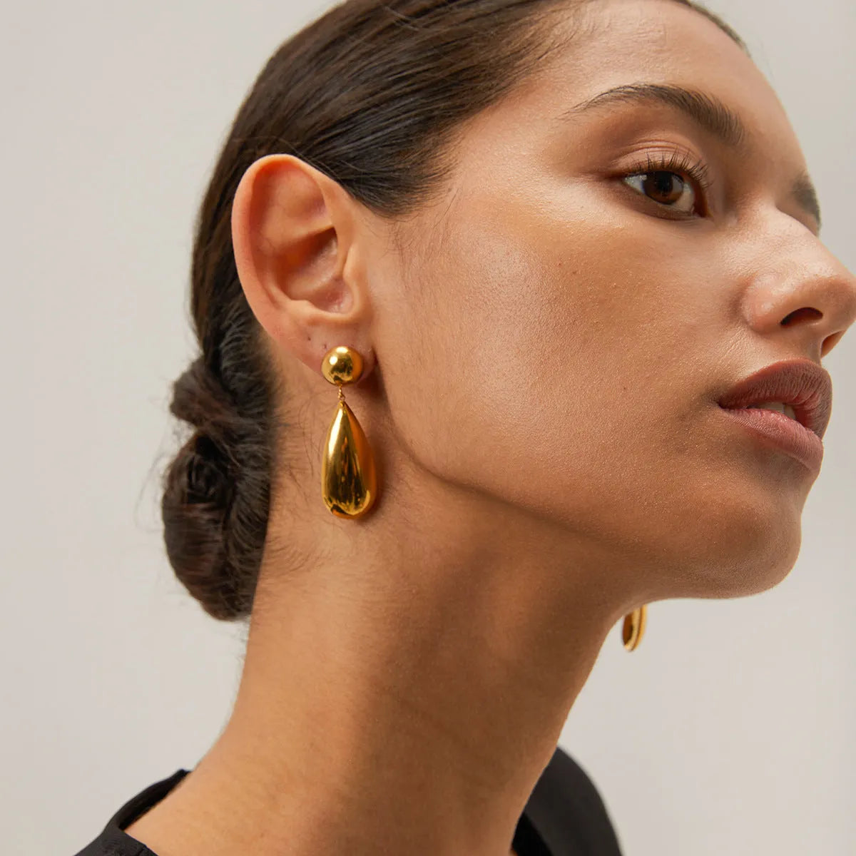 A pair of gold-coloured stainless steel earrings with a geometric water drop pendant design.