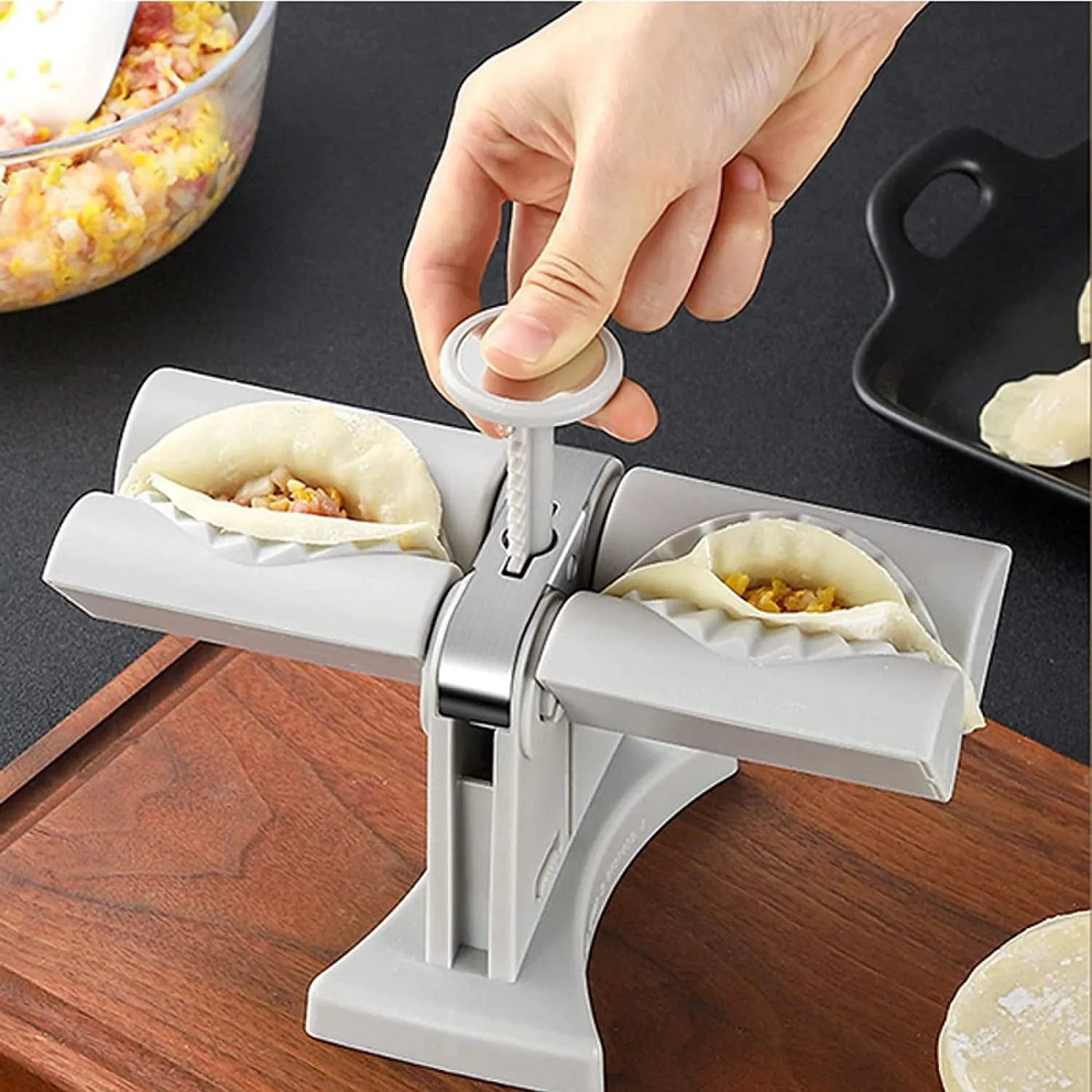 White double-head manual dumpling maker mould made from stainless steel and plastic with an anti-slip base.