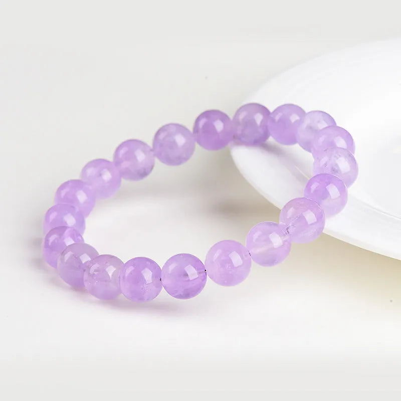 Lavender coloured amethyst crystal bracelet with round beads and a geometric water ripple design on a wrist.