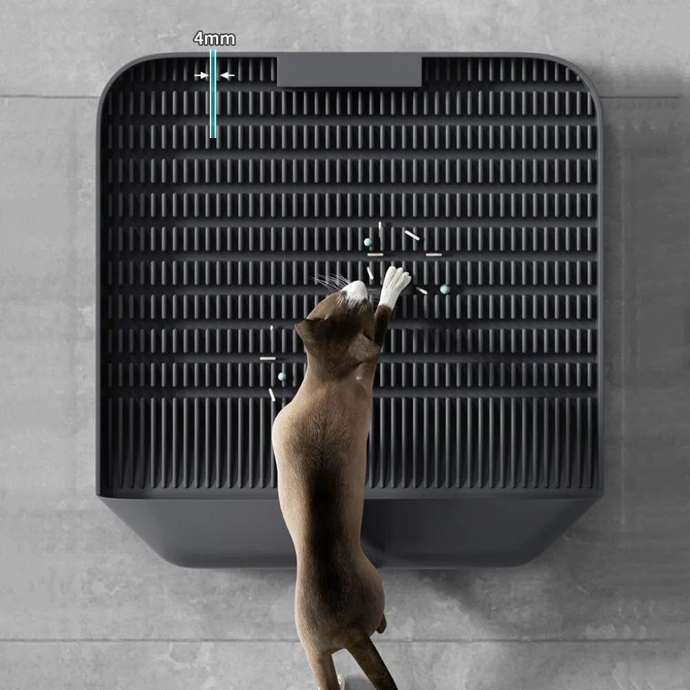 Large black cat litter pedal with slanted mouth and textured grooves beside a litter tray