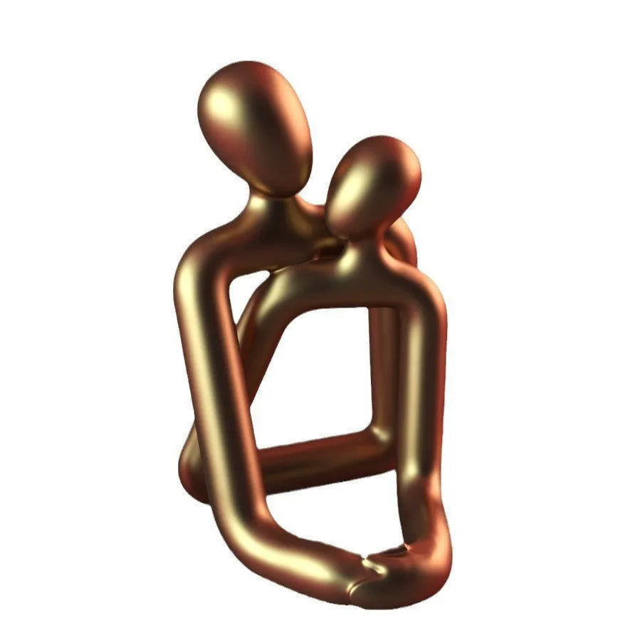 Modern minimalist loving couple resin statue in gold or milky white on a wooden surface.