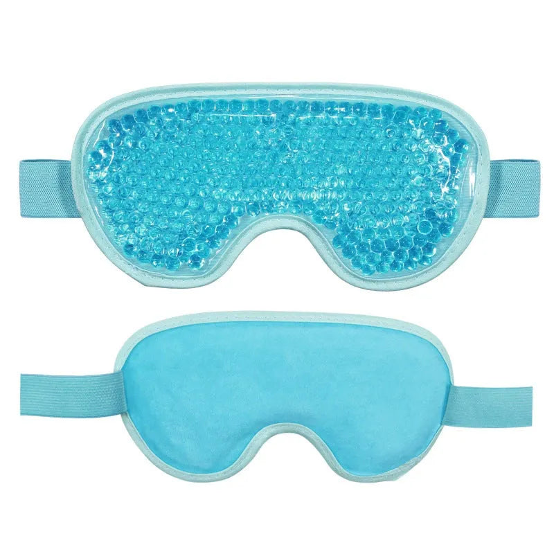 White rechargeable hot and cold compress eye massager device with included eye mask and charging cable on a plain background.