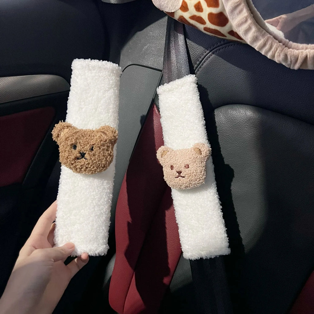 Plush cartoon bear car seat belt shoulder cover in khaki colour, shown next to a car seat.
