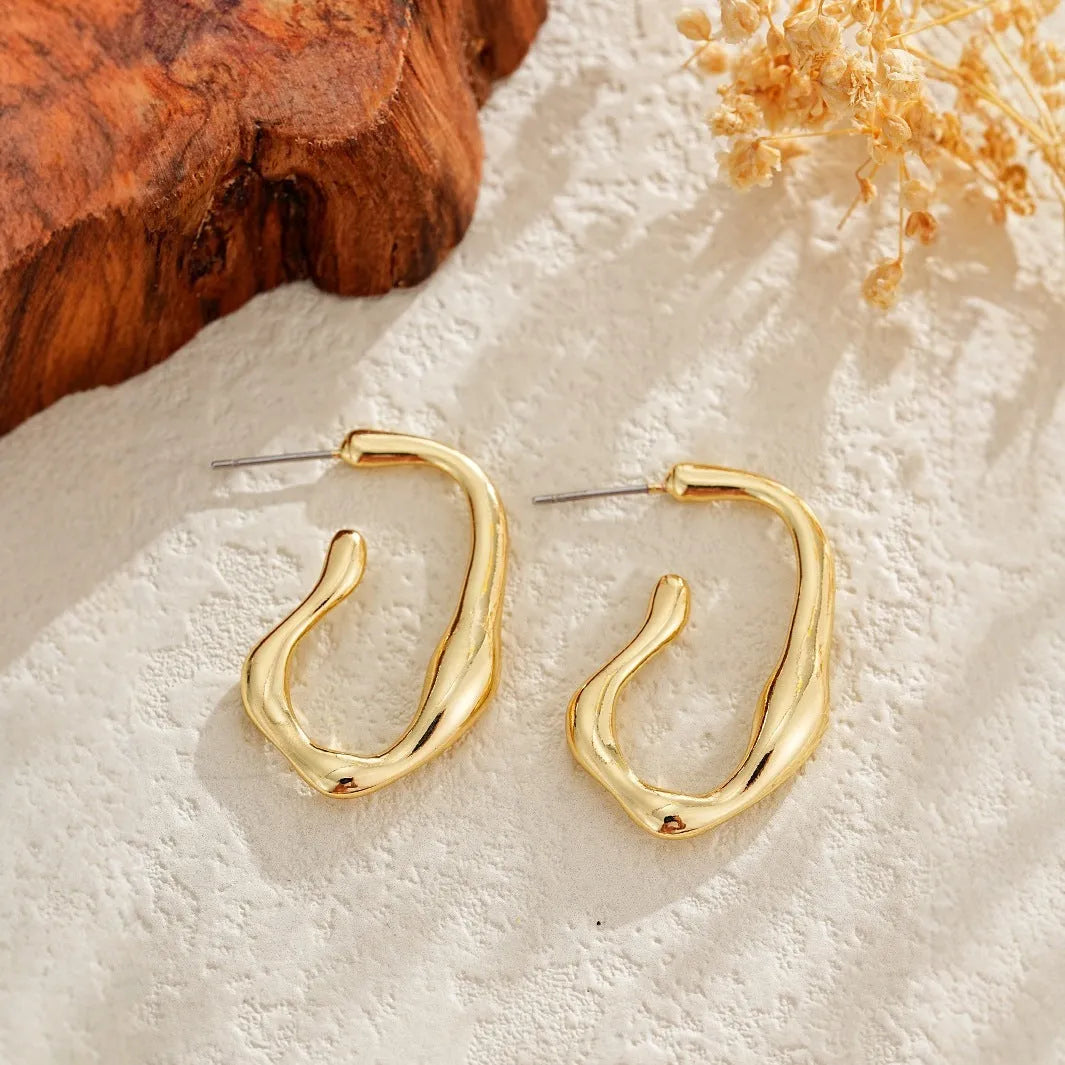 Irregular shaped minimalist drop earrings in gold tone on a clean background