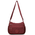 Soft grey nylon crossbody bag with an external pocket and adjustable shoulder strap.