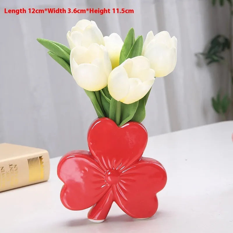 White porcelain clover-shaped ceramic vase in European style, on a desktop.