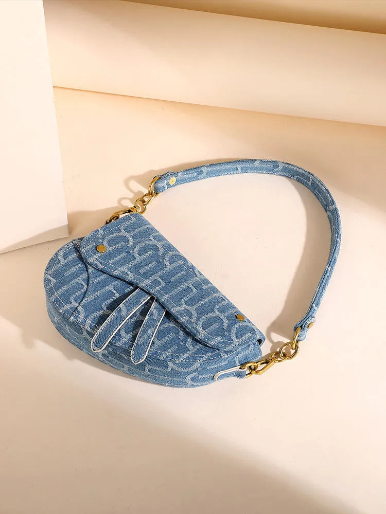 Women's vintage denim saddle bag in blue with cross-body strap and zip pocket interior