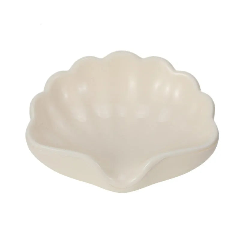 White shell-shaped plastic soap dish for bathroom counter next to sink.
