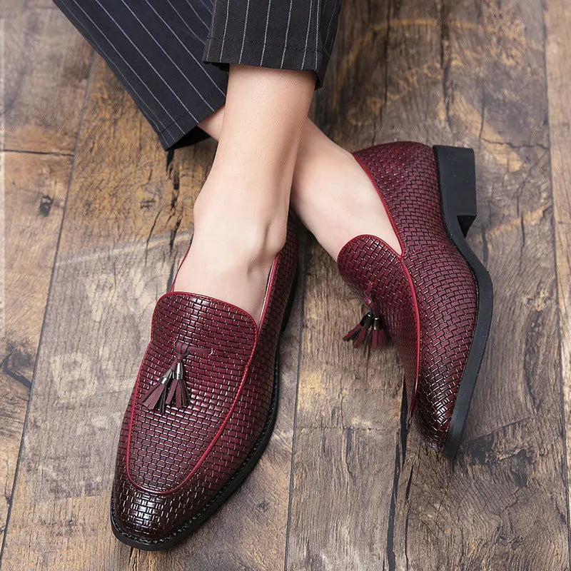 Men's black pointed slip-on business shoes with a tassel detail on the artificial PU leather upper.