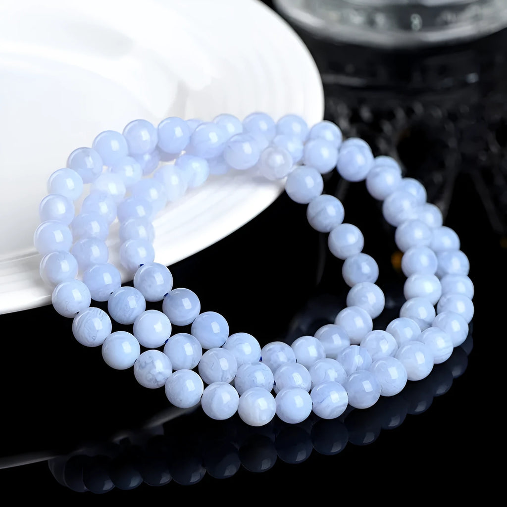 A blue agate bracelet with a natural striped pattern and scattered beads on a wrist.