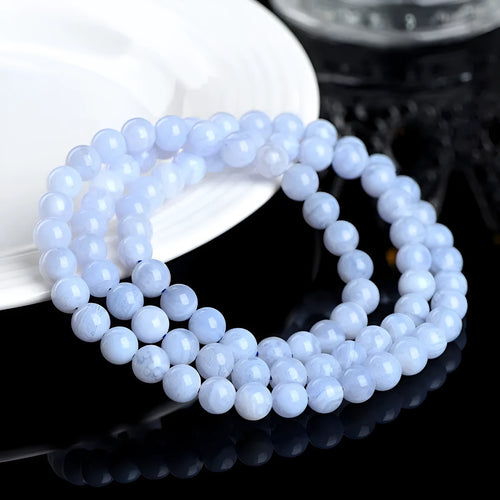 A blue agate bracelet with a natural striped pattern and scattered beads on a wrist.