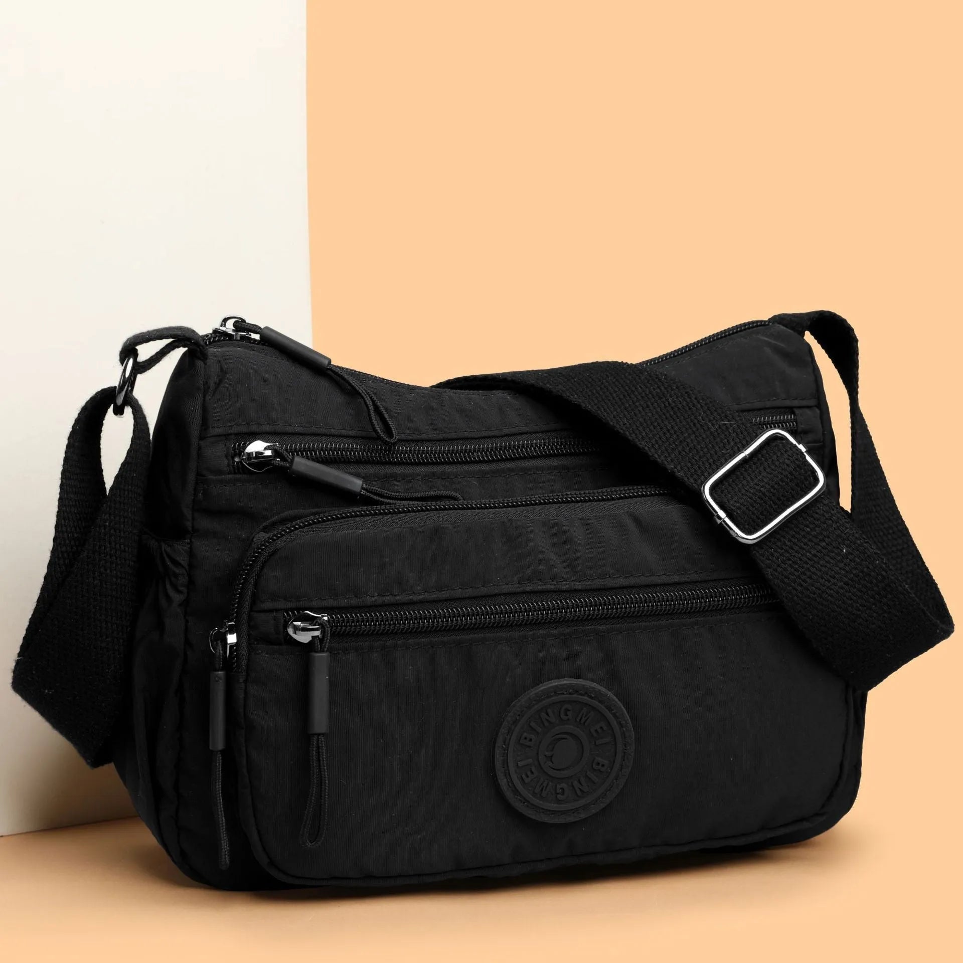 Soft grey nylon crossbody bag with an external pocket and adjustable shoulder strap.