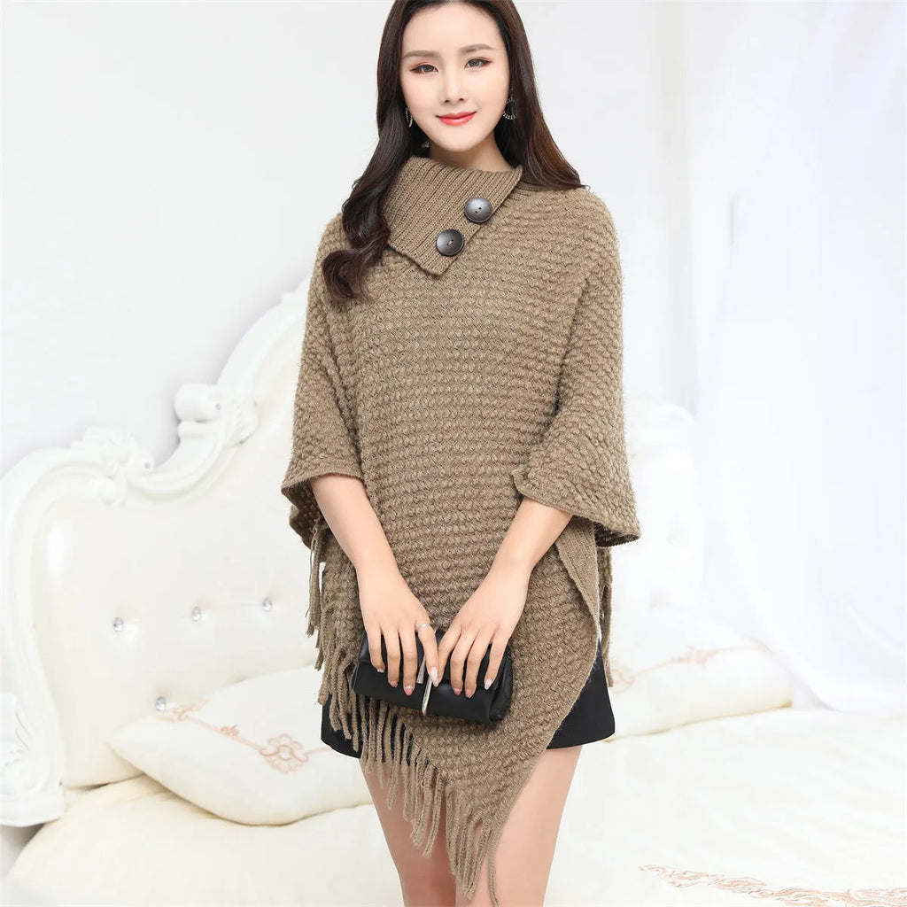 Dot-patterned acrylic knitted shawl cloak in apricot colour, laid flat.