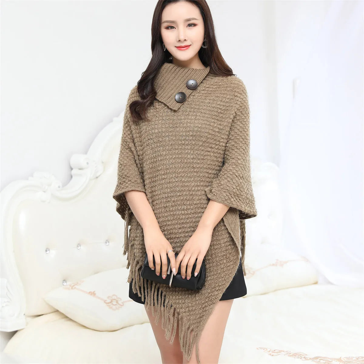 Dot-patterned acrylic knitted shawl cloak in apricot colour, laid flat.