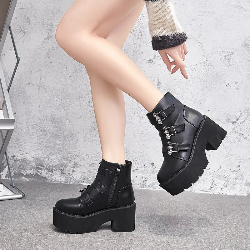 Black women's punk ankle boots with bat buckle and side zip on a thick sole.