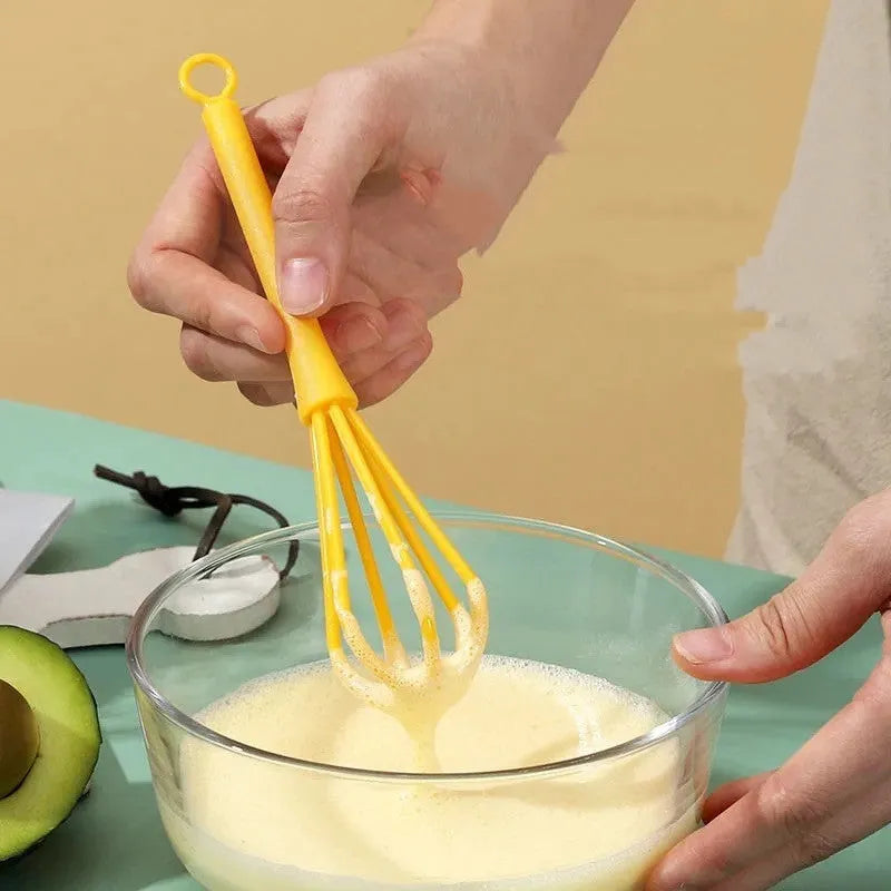 Plastic creative mini manual eggbeater in green and yellow, size 4x18.5 cm, on kitchen counter