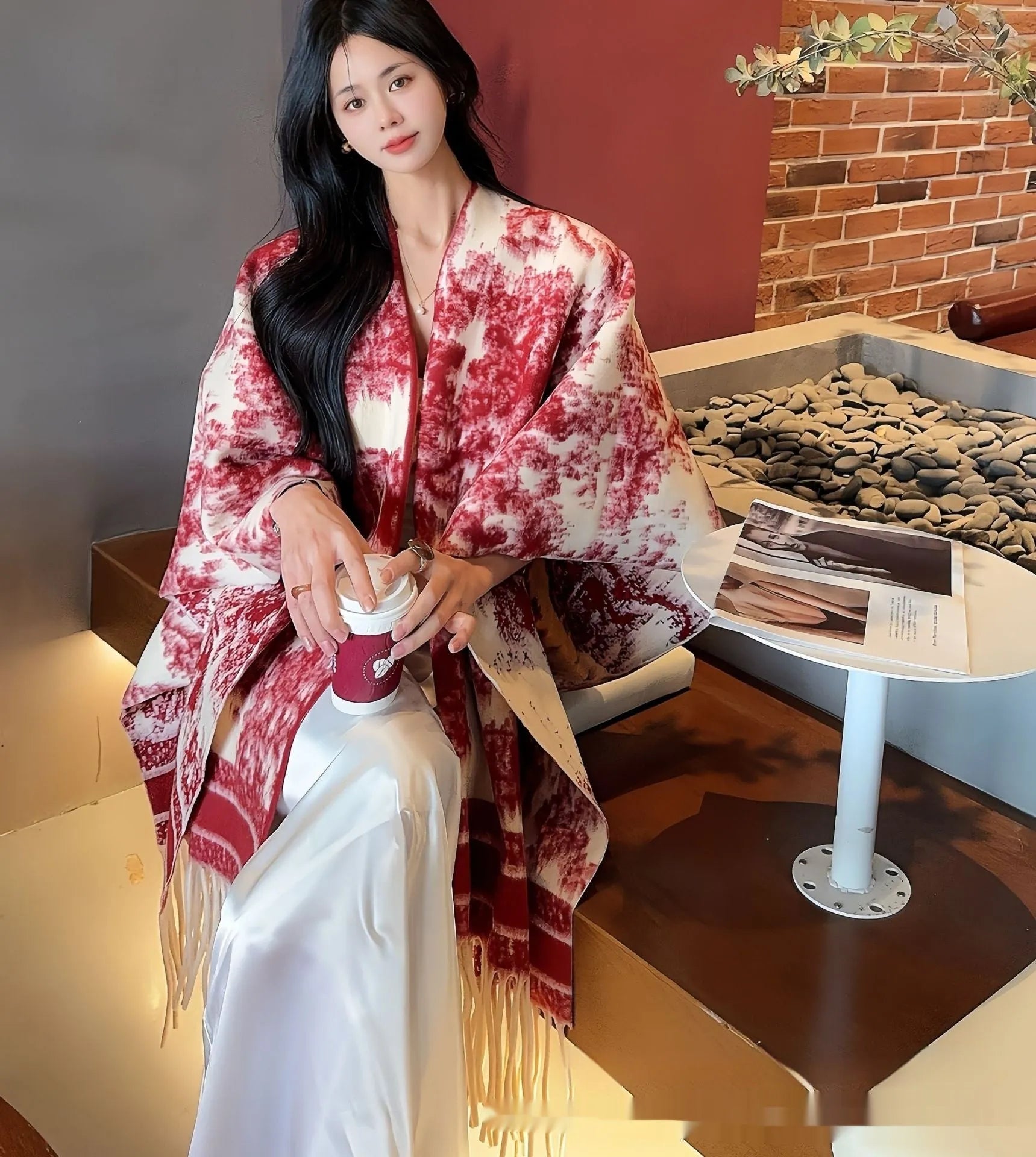 Woman wearing a printed tassel-trim scarf cape draped over shoulders.