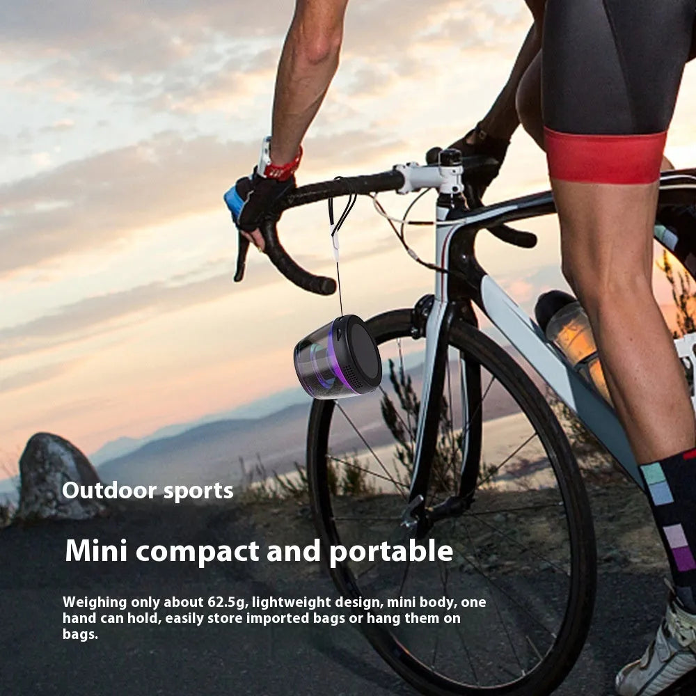 Black portable Bluetooth mini speaker with ambient light on a metallic surface, showing its magnetic base.