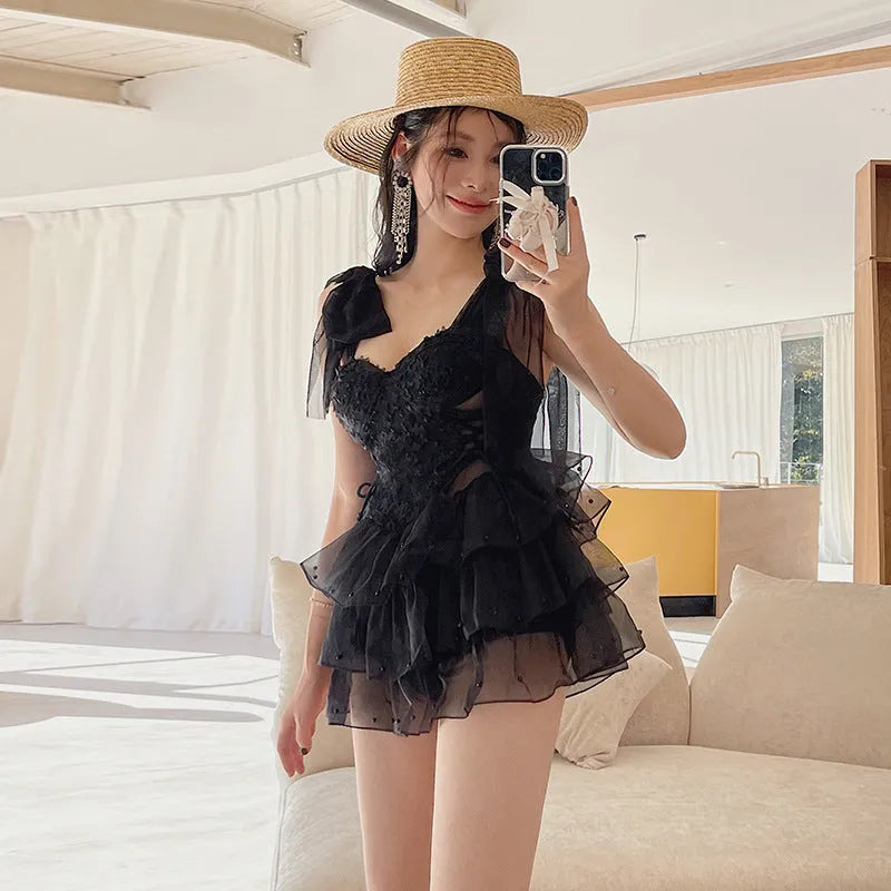 Black conservative one-piece swimsuit with gathered chest detail for belly coverage.