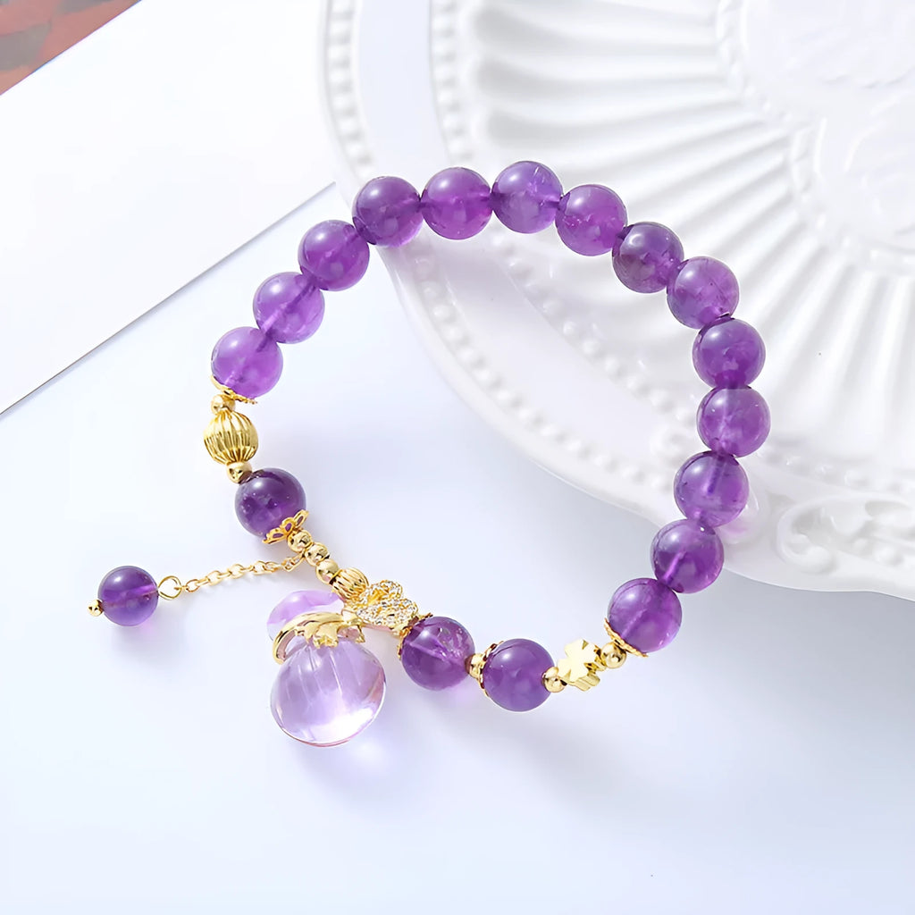 Purple crystal bracelet with ethnic money bag pendant and peace buckle closure on wrist