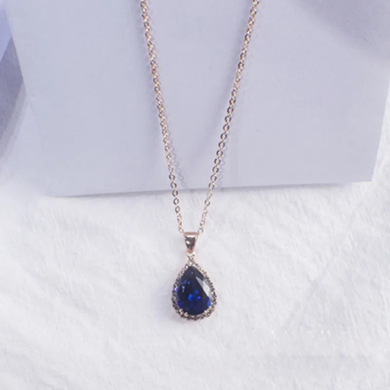 Close-up of a rose gold tone drop shape necklace with rhinestone details on a geometric pendant.