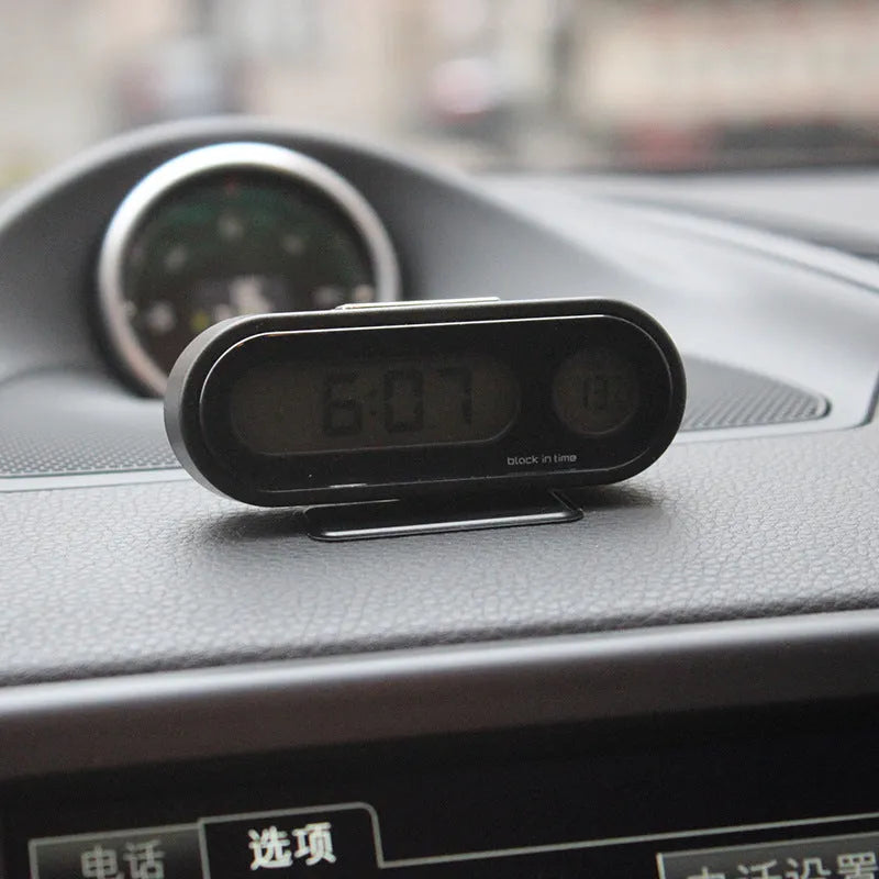 Black digital car dashboard clock and thermometer with LED display on an adjustable mounting bracket.
