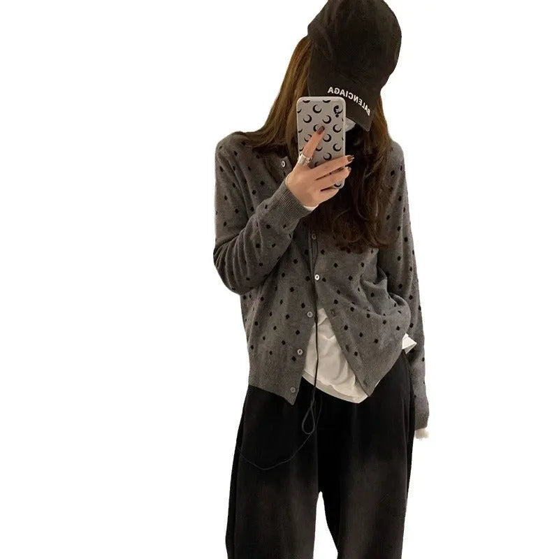 Grey dot patterned women's knitted cardigan with crochet flower details on a hanger.