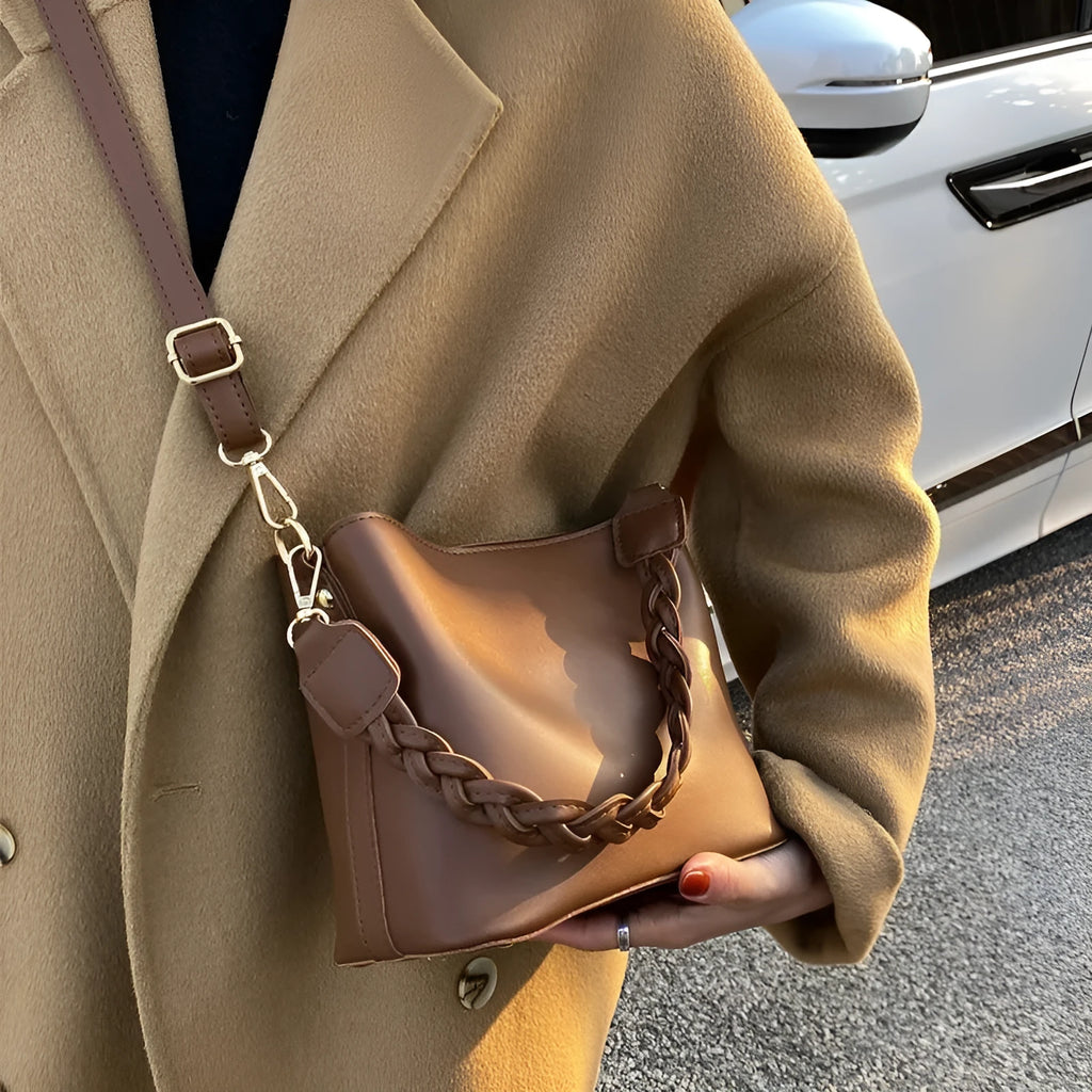 Khaki coloured PU leather one-shoulder crossbody bucket bag with woven detail on the front.