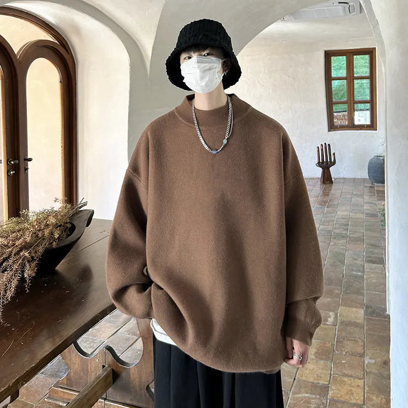 Man wearing a loose fit, solid colour round neck pullover sweater.