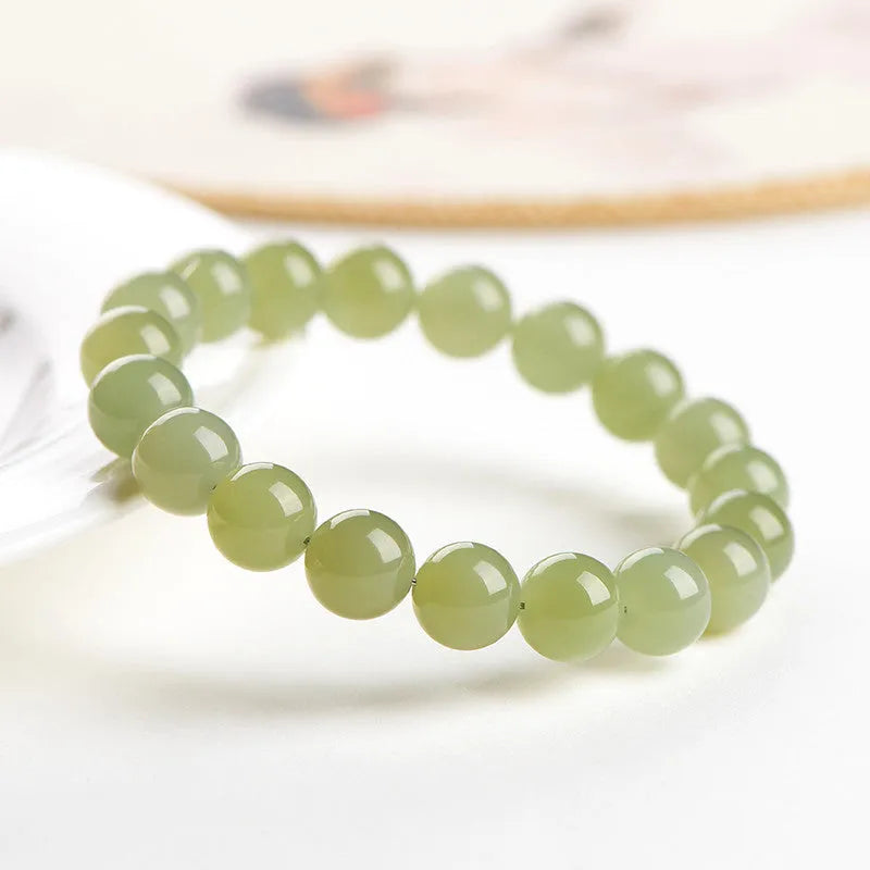 Unisex Hetian Jade ball bracelet with polished beads in clear colours on a wrist.