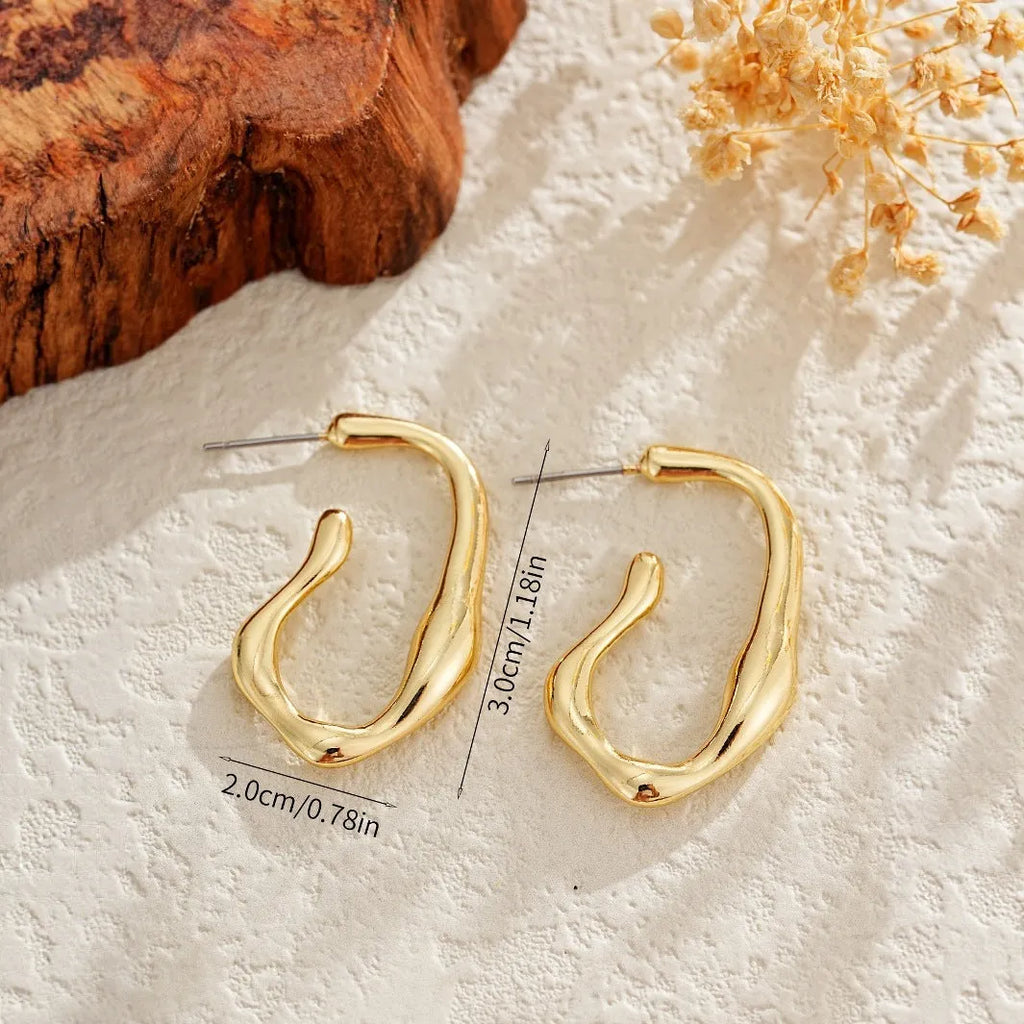 Irregular shaped minimalist drop earrings in gold tone on a clean background