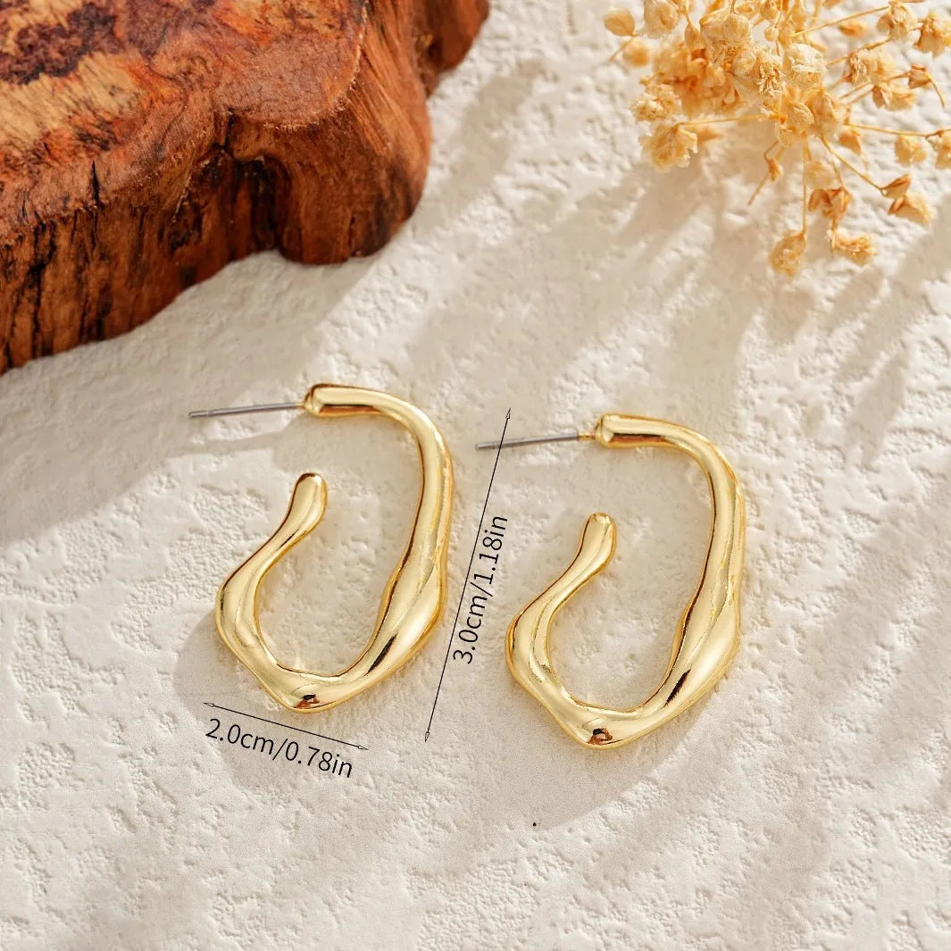 Irregular shaped minimalist drop earrings in gold tone on a clean background