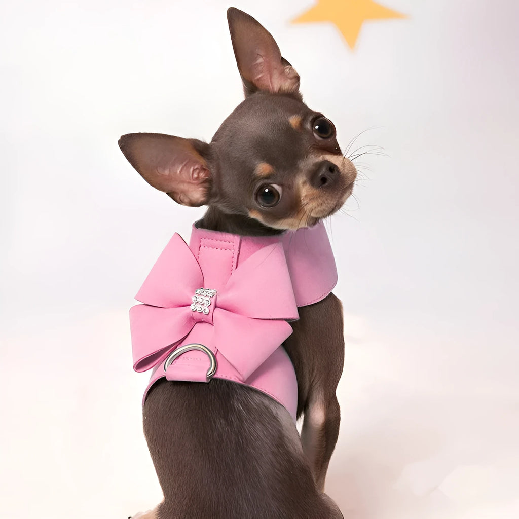 A pink microfiber dog chest strap with a large decorative bowknot and metal buckle.