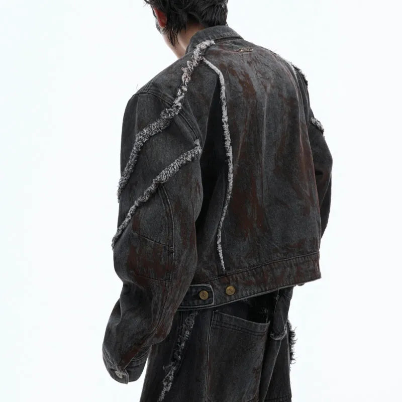 Black denim coat and trouser set with distressed raw edges and a splash-dye gradient pattern.
