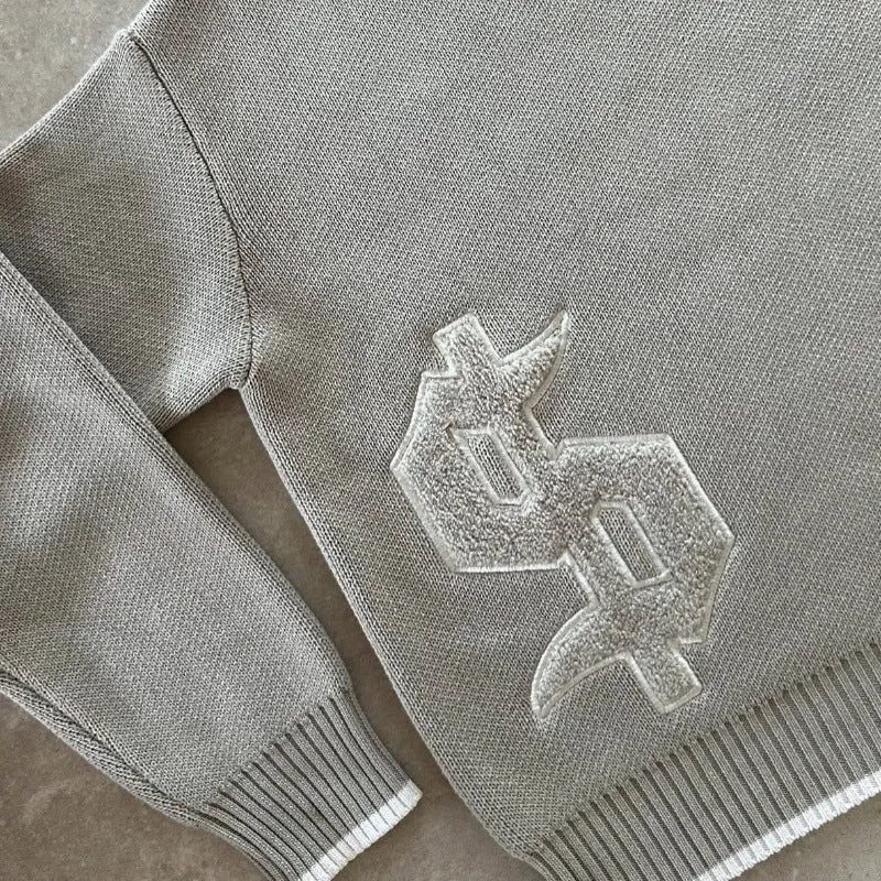 Gray loose-fitting Jacquard knitwear coat with long sleeves on a hanger.