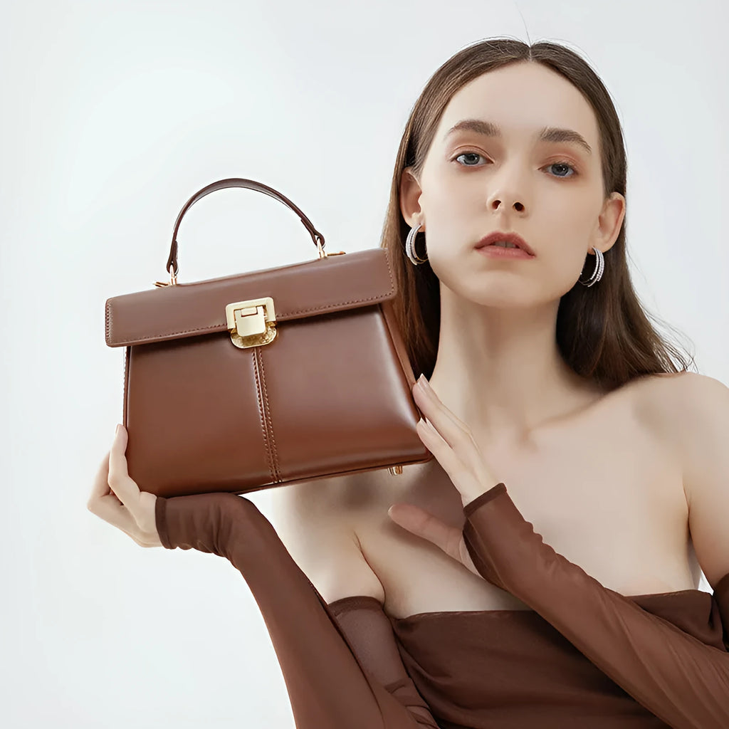 Black leather women's shoulder bag with vachette clasp, shown open to reveal internal zippered pocket.