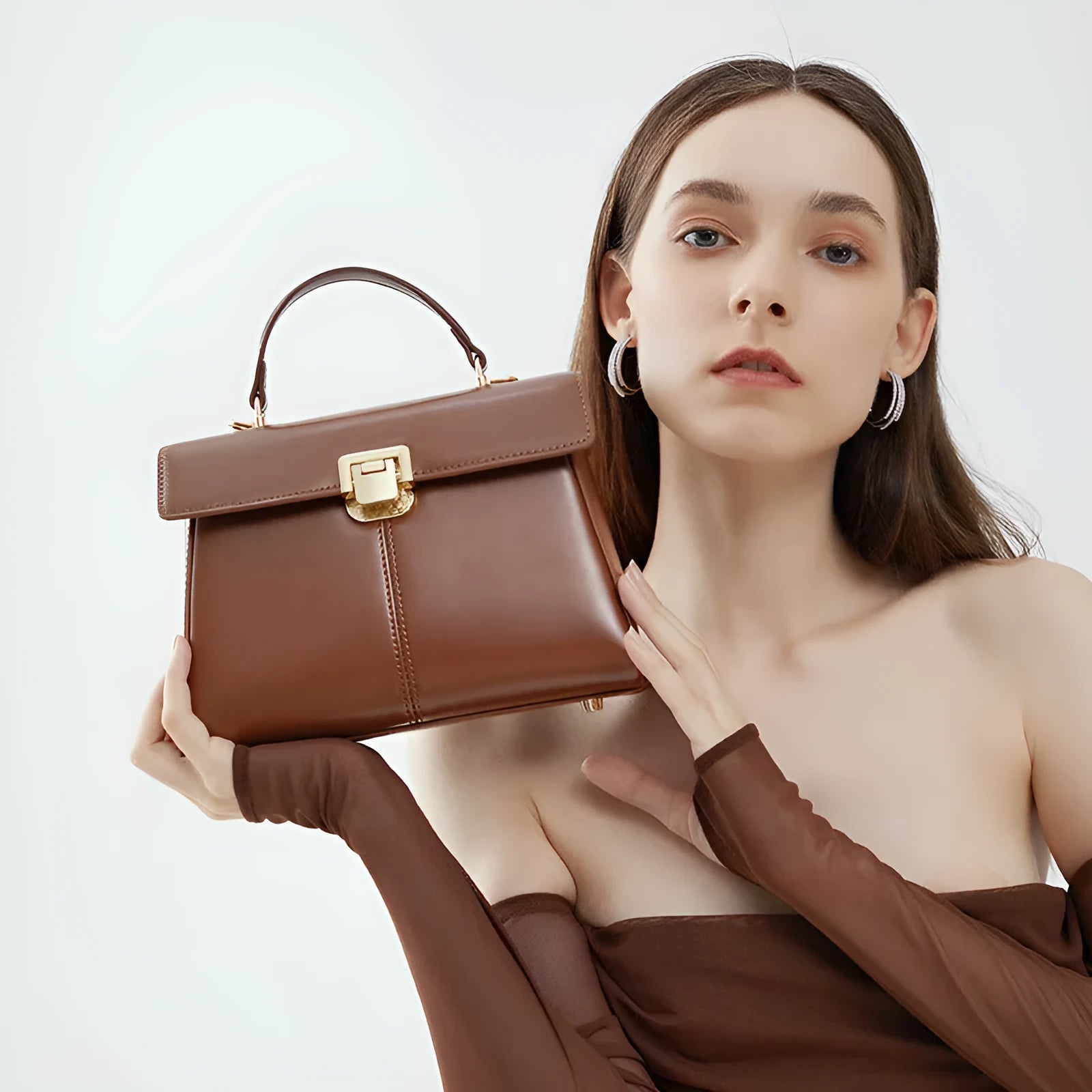 Black leather women's shoulder bag with vachette clasp, shown open to reveal internal zippered pocket.
